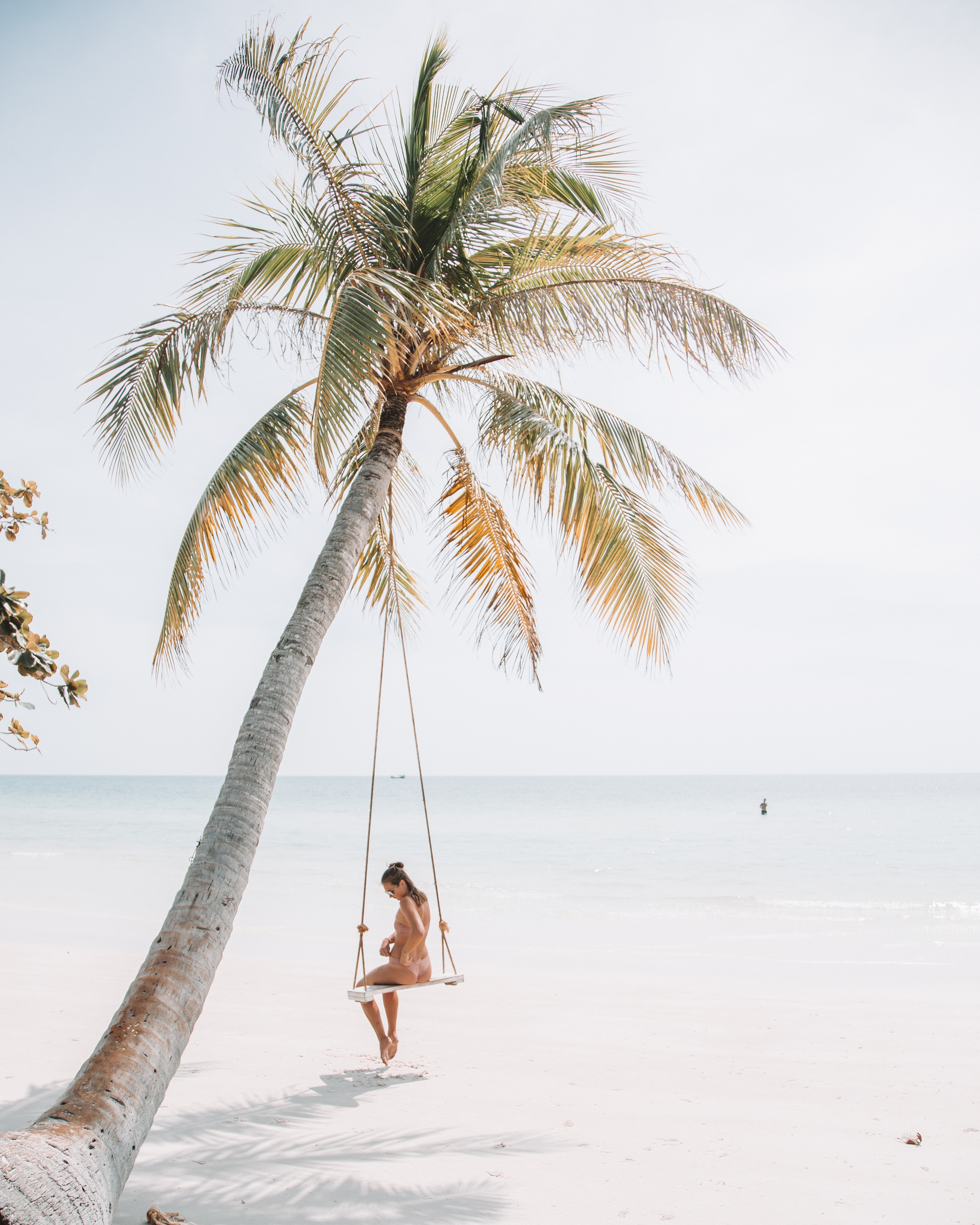 Woman sitting on a swing on the beach