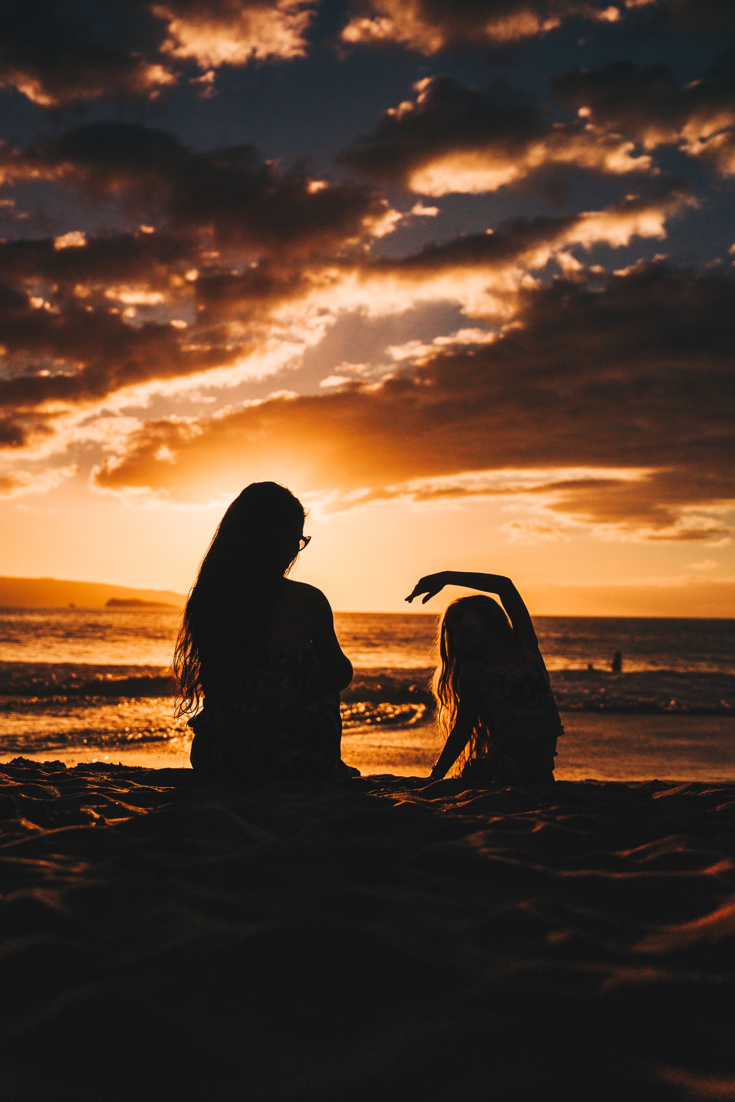 Mother and daughter on beach at sunset