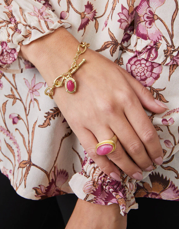woman wearing gold toggle pink stone bracelet and ring