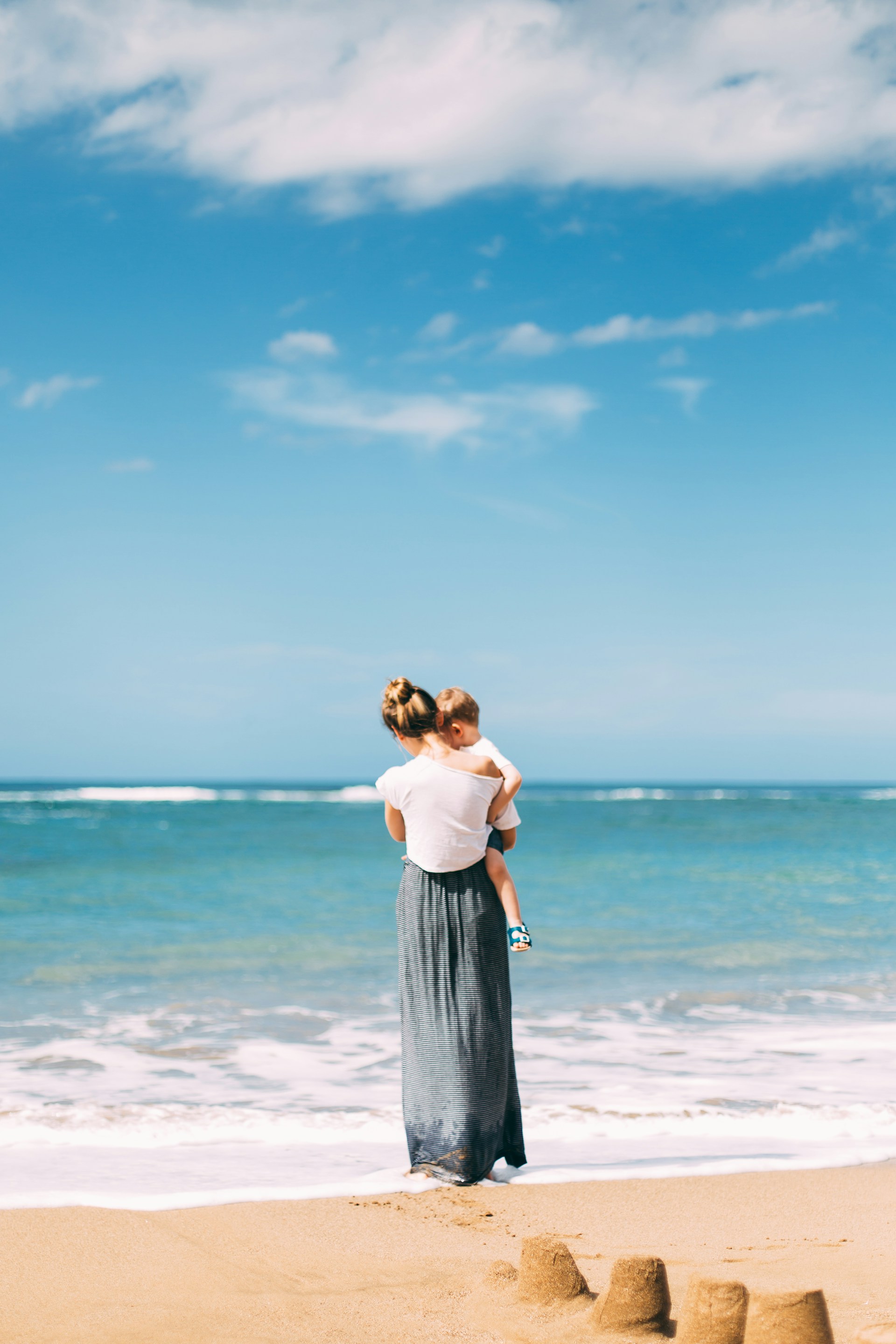 woman carrying toddler on the beach
