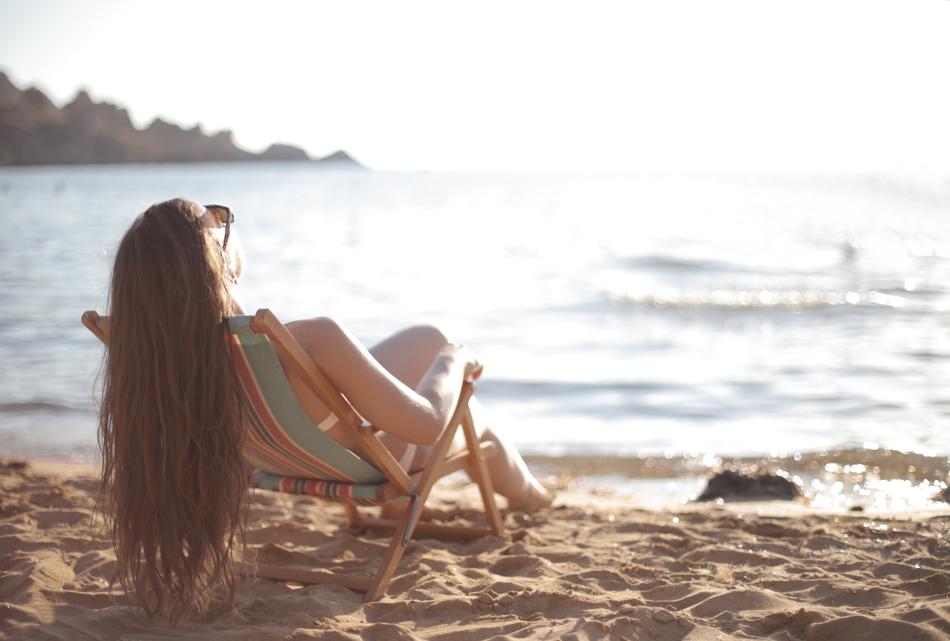 woman reclining beach chair at the beach File name: women’s-beach-bag-checklist